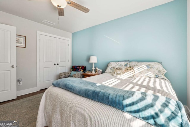 bedroom with ceiling fan, dark wood-type flooring, and a closet