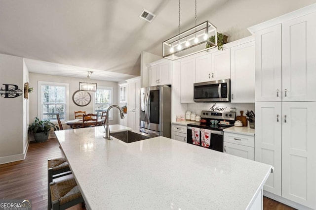 kitchen with sink, stainless steel appliances, a kitchen island with sink, and hanging light fixtures