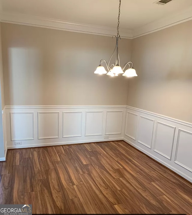 spare room with dark wood-type flooring, crown molding, and a notable chandelier