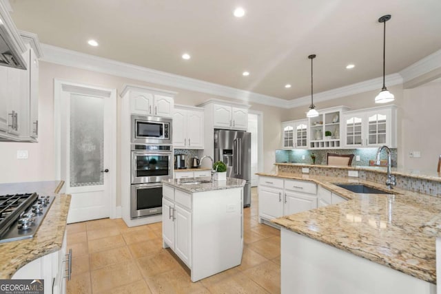 kitchen featuring sink, white cabinetry, hanging light fixtures, stainless steel appliances, and a kitchen island with sink