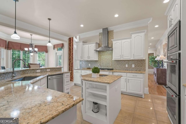 kitchen with sink, white cabinetry, appliances with stainless steel finishes, a kitchen island, and wall chimney range hood