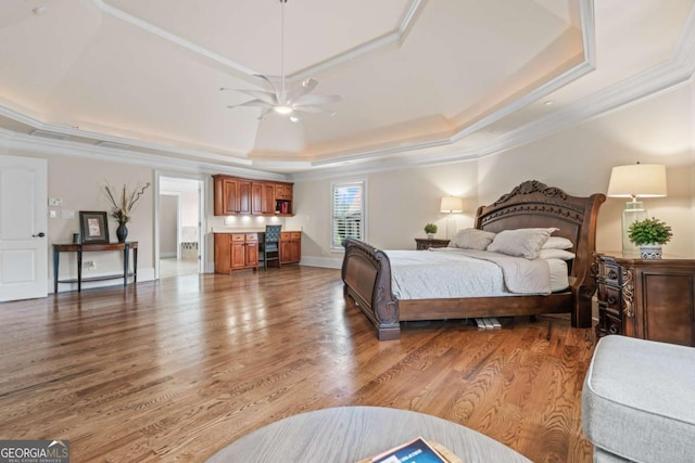 bedroom featuring hardwood / wood-style flooring, crown molding, ceiling fan, and a tray ceiling