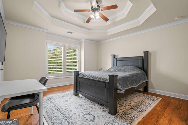 bedroom featuring ceiling fan, ornamental molding, dark hardwood / wood-style floors, and a raised ceiling