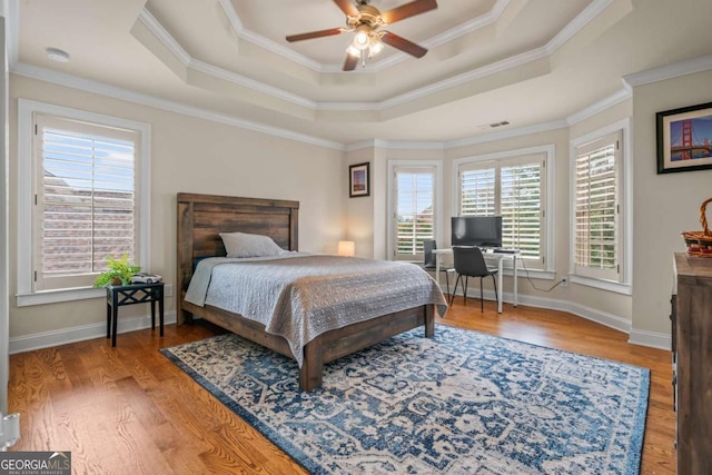 bedroom featuring ceiling fan, a raised ceiling, and multiple windows