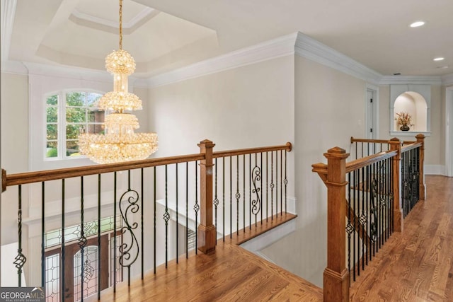 corridor featuring hardwood / wood-style flooring, crown molding, a chandelier, and a tray ceiling