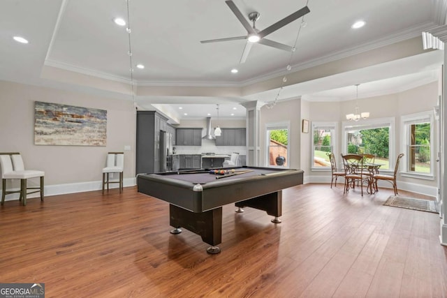 playroom featuring pool table, wood-type flooring, ornamental molding, a raised ceiling, and ceiling fan with notable chandelier