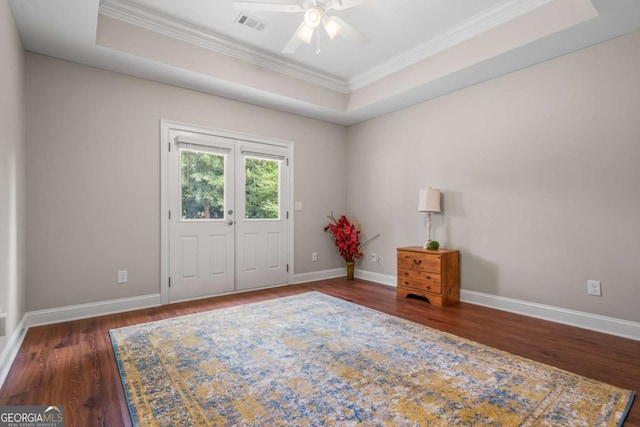 empty room featuring crown molding, dark wood-type flooring, a raised ceiling, and ceiling fan