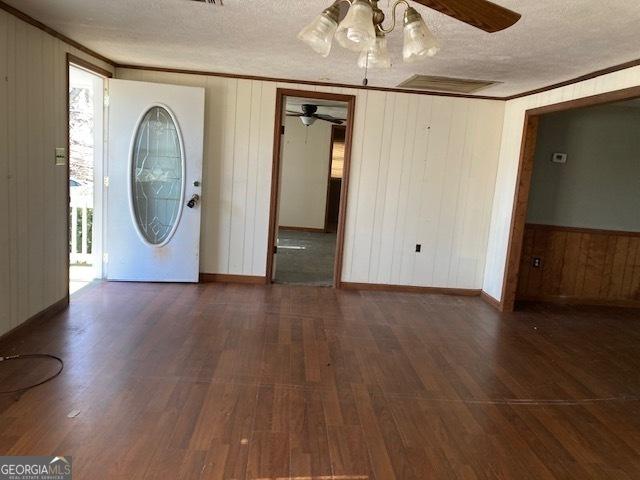 entrance foyer featuring a textured ceiling, ceiling fan, ornamental molding, and dark hardwood / wood-style floors