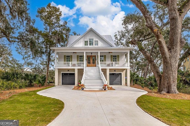 coastal home featuring a garage, a porch, a front yard, and french doors