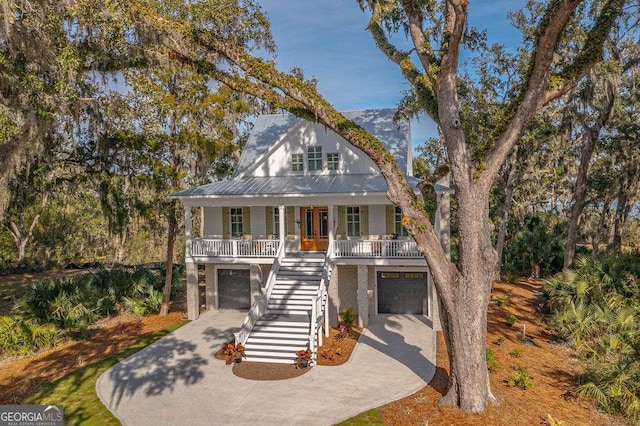 coastal inspired home with french doors, covered porch, stairway, an attached garage, and metal roof