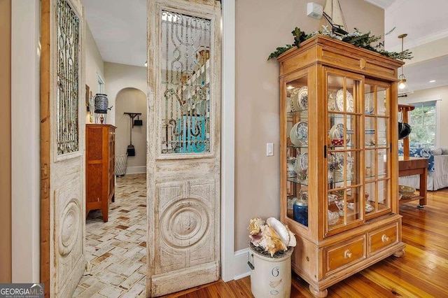 hallway featuring arched walkways, baseboards, and wood finished floors