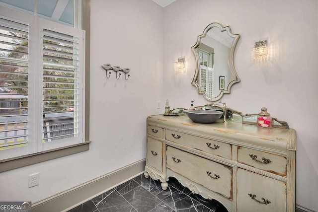 bathroom with marble finish floor, vanity, and baseboards