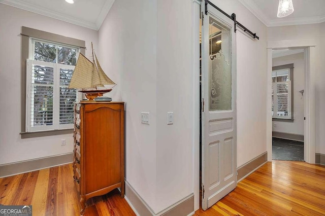 hall with ornamental molding, a barn door, and light hardwood / wood-style flooring