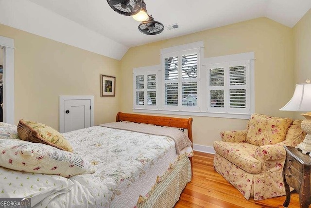 bedroom featuring light wood-type flooring, lofted ceiling, visible vents, and baseboards