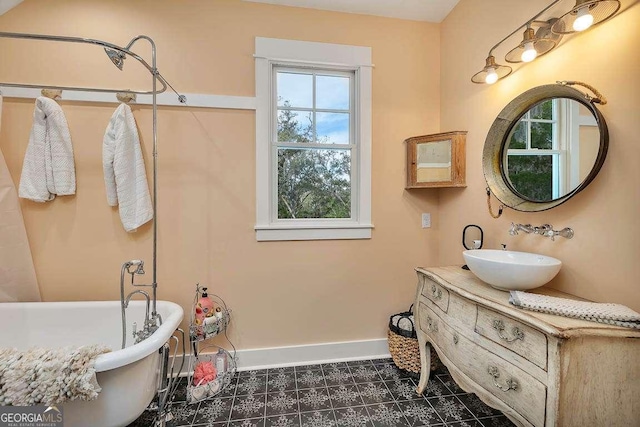 bathroom with a freestanding bath, vanity, and baseboards