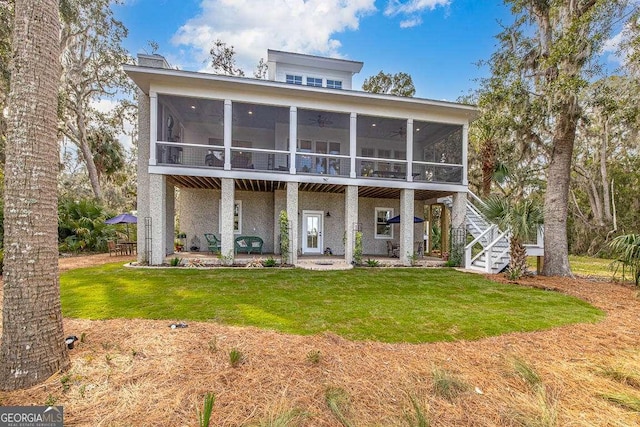 rear view of property with a patio area, a sunroom, and a lawn