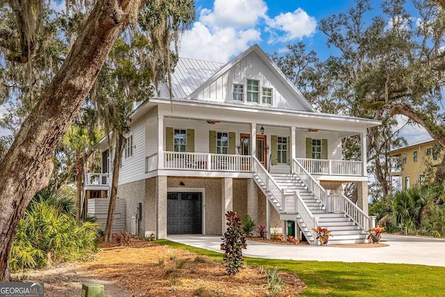 coastal home featuring a garage, ceiling fan, and covered porch