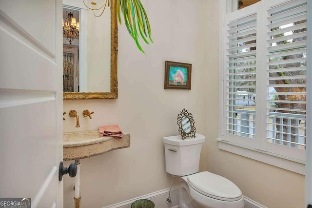 bathroom featuring an inviting chandelier, a wealth of natural light, and toilet