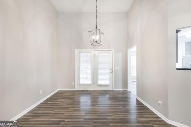 interior space featuring a high ceiling, dark wood-type flooring, and a notable chandelier