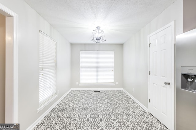 empty room featuring a textured ceiling and a notable chandelier