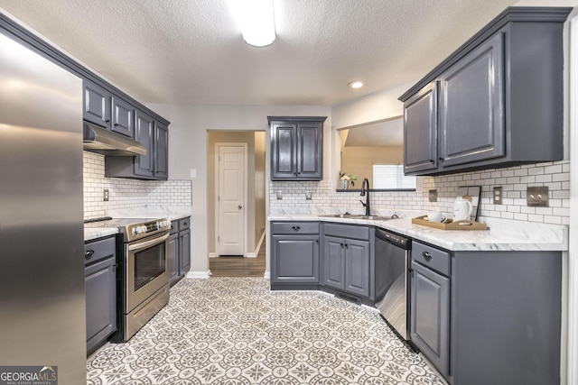 kitchen with a textured ceiling, stainless steel appliances, decorative backsplash, gray cabinetry, and sink