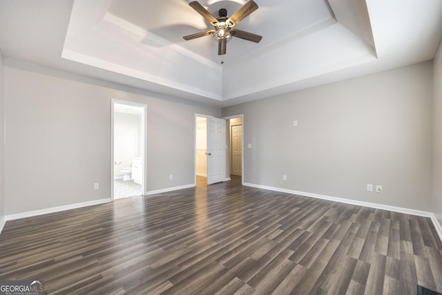 empty room featuring ceiling fan, dark hardwood / wood-style flooring, and a tray ceiling