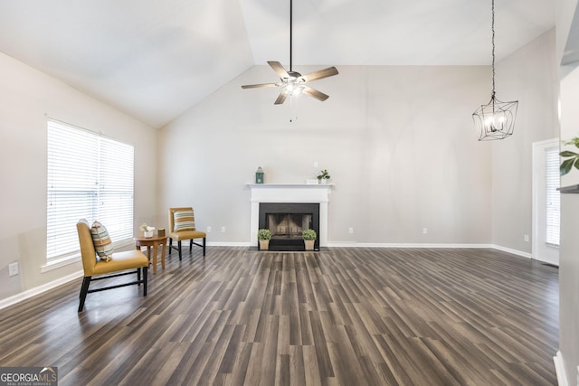 sitting room featuring ceiling fan with notable chandelier, lofted ceiling, a wealth of natural light, and dark hardwood / wood-style floors