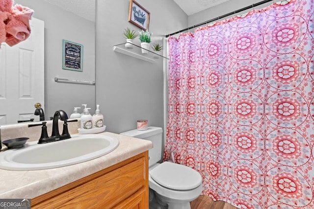 bathroom with hardwood / wood-style flooring, a textured ceiling, toilet, and vanity