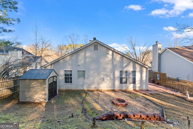 rear view of property with an outdoor fire pit and a shed