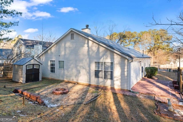 back of house with an outdoor fire pit and a shed