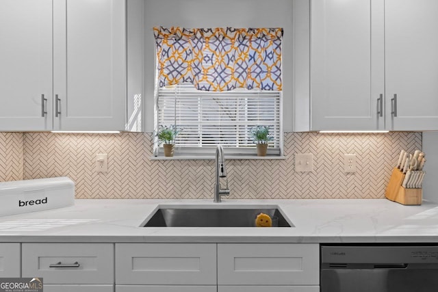 kitchen featuring light stone countertops, sink, white cabinets, and stainless steel dishwasher