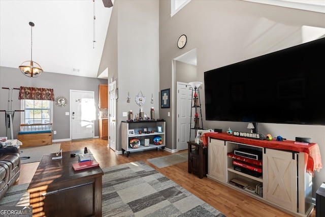 living room featuring ceiling fan with notable chandelier, high vaulted ceiling, and wood-type flooring