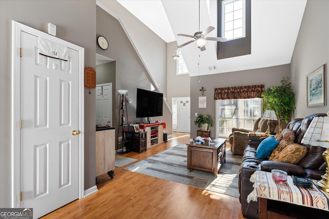 living room featuring a towering ceiling, ceiling fan, and light hardwood / wood-style floors