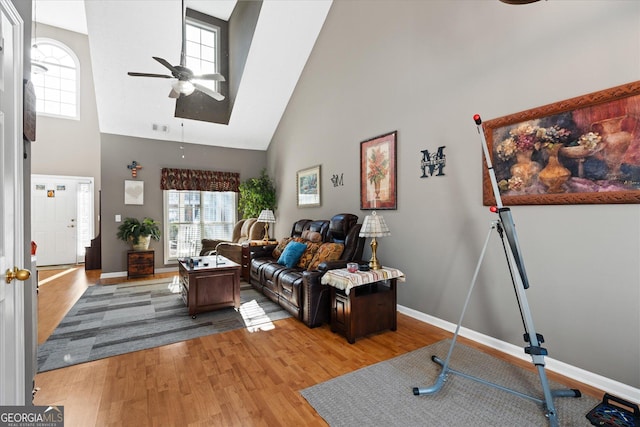 living room featuring a high ceiling, light wood-type flooring, and ceiling fan