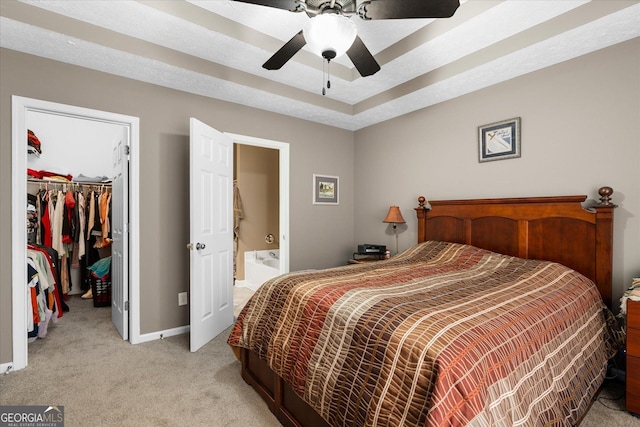 bedroom featuring a closet, ensuite bath, light colored carpet, ceiling fan, and a walk in closet