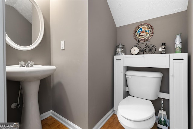 bathroom with a textured ceiling, toilet, lofted ceiling, and hardwood / wood-style flooring