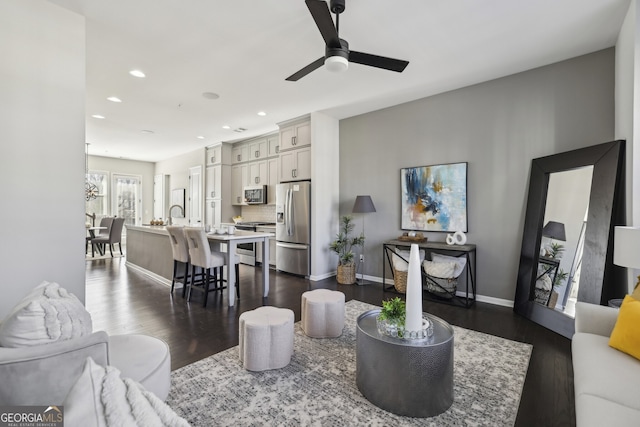 living room with ceiling fan, sink, and dark hardwood / wood-style floors