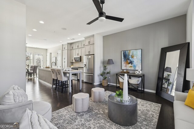 living room with ceiling fan and dark hardwood / wood-style flooring