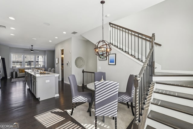 dining room with ceiling fan with notable chandelier and dark wood-type flooring