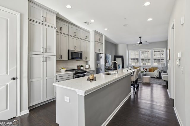 kitchen with stainless steel appliances, sink, gray cabinets, ceiling fan, and dark hardwood / wood-style floors