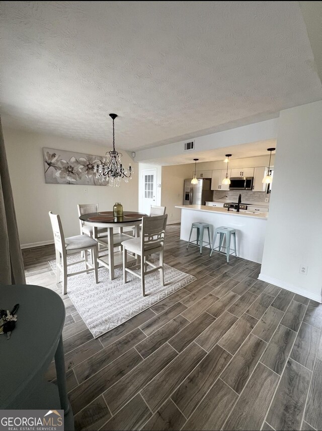 148 N Stewart Ln, Griffin, GA 30224 - dining area with wood tiled floor, visible vents, a chandelier, and a textured ceiling