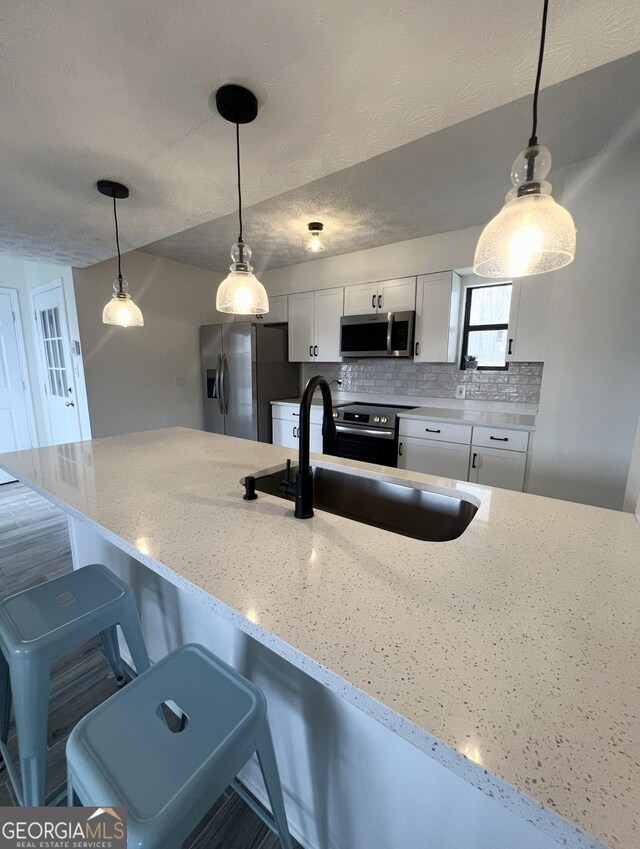 148 N Stewart Ln, Griffin, GA 30224 - kitchen with light stone countertops, decorative backsplash, appliances with stainless steel finishes, white cabinets, and a sink