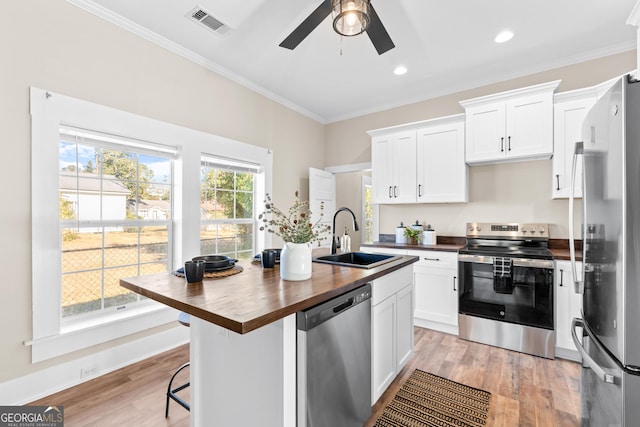 kitchen featuring appliances with stainless steel finishes, white cabinetry, butcher block countertops, and sink