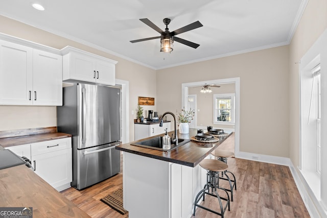 kitchen featuring light hardwood / wood-style floors, stainless steel fridge, butcher block countertops, white cabinetry, and sink