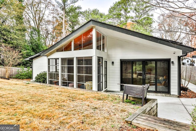 back of property with a lawn, a sunroom, and a patio