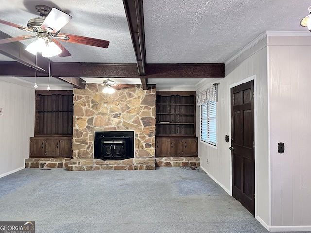 unfurnished living room with ceiling fan, carpet floors, a textured ceiling, ornamental molding, and beamed ceiling