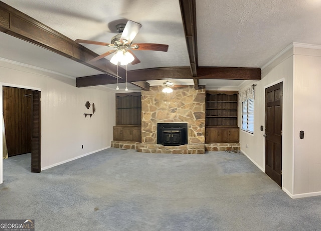 unfurnished living room with ceiling fan, a wood stove, carpet floors, a textured ceiling, and built in shelves