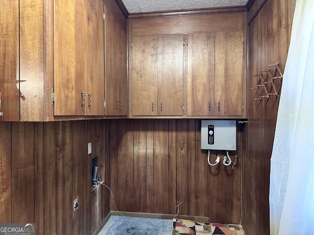 laundry room with washer hookup, wood walls, and cabinets