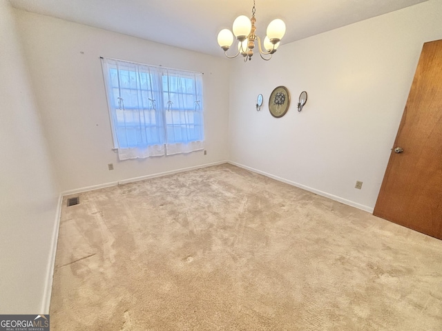 spare room featuring light carpet and an inviting chandelier