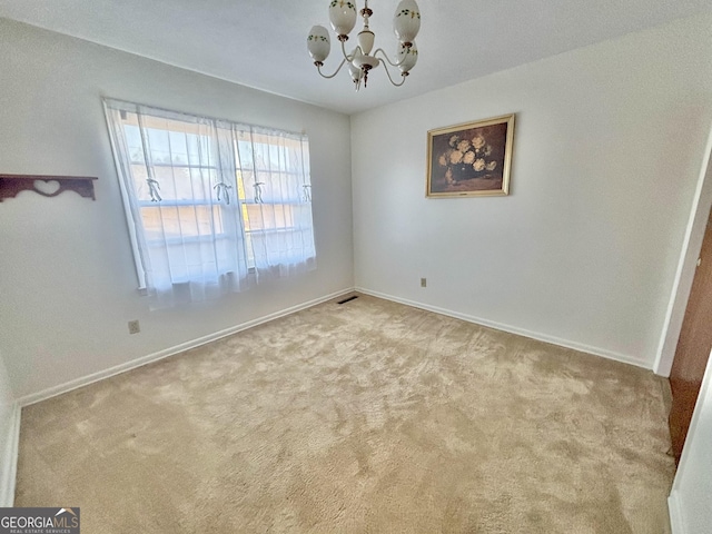 empty room featuring light carpet and a notable chandelier